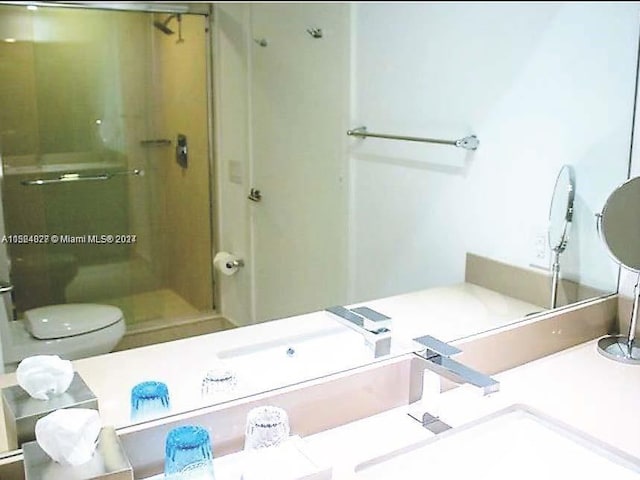 bathroom with sink, a shower with shower door, and toilet