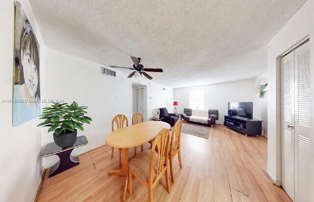 dining room featuring a textured ceiling, ceiling fan, and light wood-type flooring