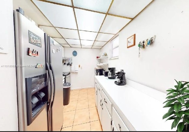 kitchen with white cabinets, stainless steel fridge with ice dispenser, light tile floors, and a drop ceiling