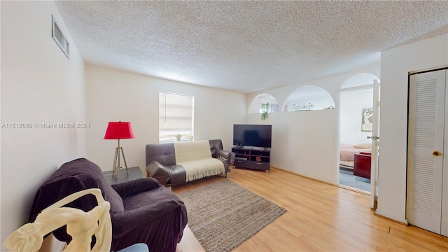 living room with a textured ceiling and light wood-type flooring