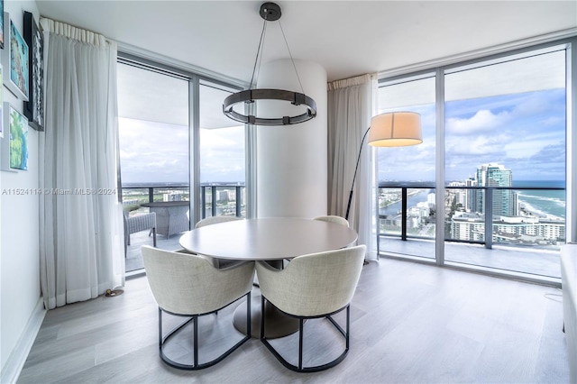 dining space featuring a water view, a wall of windows, light hardwood / wood-style flooring, and an inviting chandelier