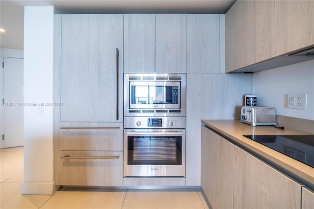 kitchen with light brown cabinets, stainless steel appliances, and light tile floors