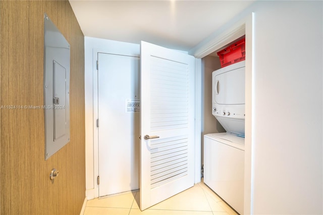 laundry room featuring light tile floors and stacked washer / dryer