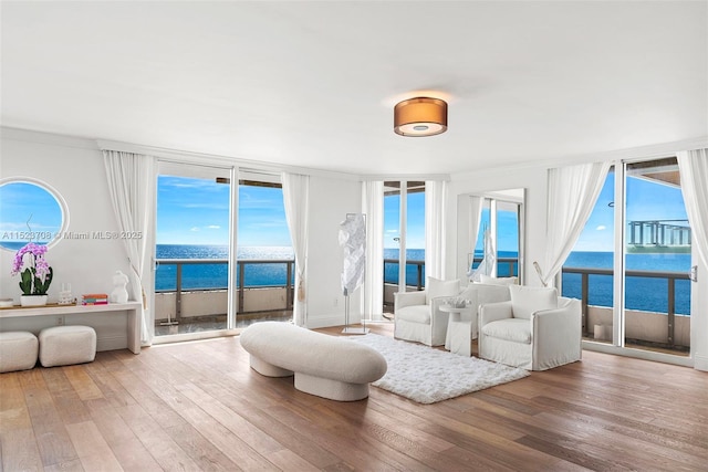 interior space with hardwood / wood-style flooring, expansive windows, a water view, and crown molding