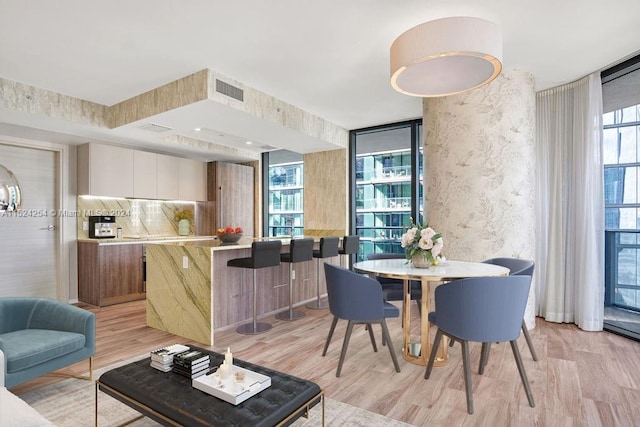 dining space featuring plenty of natural light, a wall of windows, and light wood-type flooring