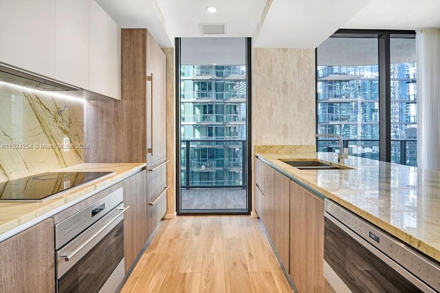 kitchen with light hardwood / wood-style floors, stainless steel oven, black electric stovetop, white cabinets, and dishwasher