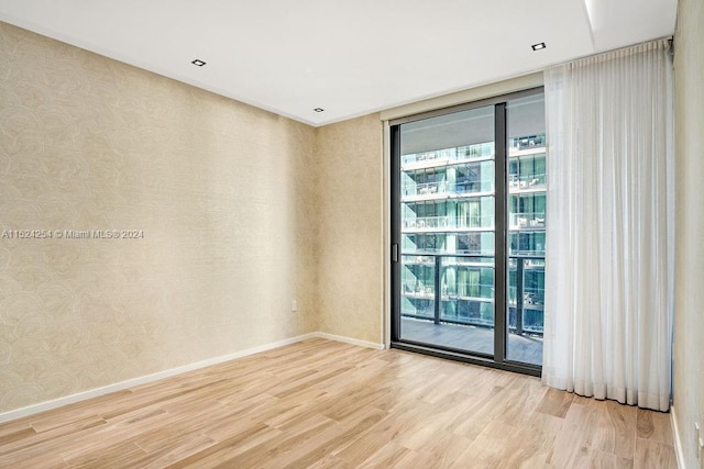 empty room with light hardwood / wood-style floors and a wall of windows