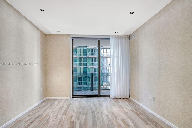 unfurnished room featuring expansive windows, a wealth of natural light, and light hardwood / wood-style flooring