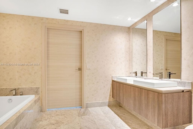 bathroom with tiled tub, dual sinks, large vanity, and tile flooring