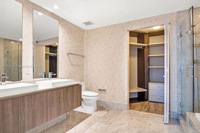 bathroom with double vanity, toilet, a shower with shower door, and tile flooring