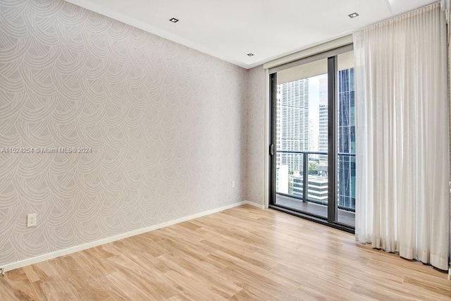 empty room featuring light hardwood / wood-style floors, a wall of windows, and a wealth of natural light