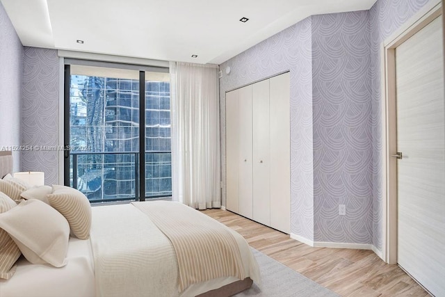 bedroom with floor to ceiling windows and light hardwood / wood-style floors