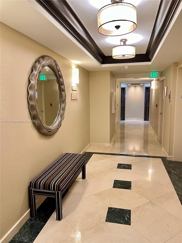 hall with a tray ceiling and crown molding