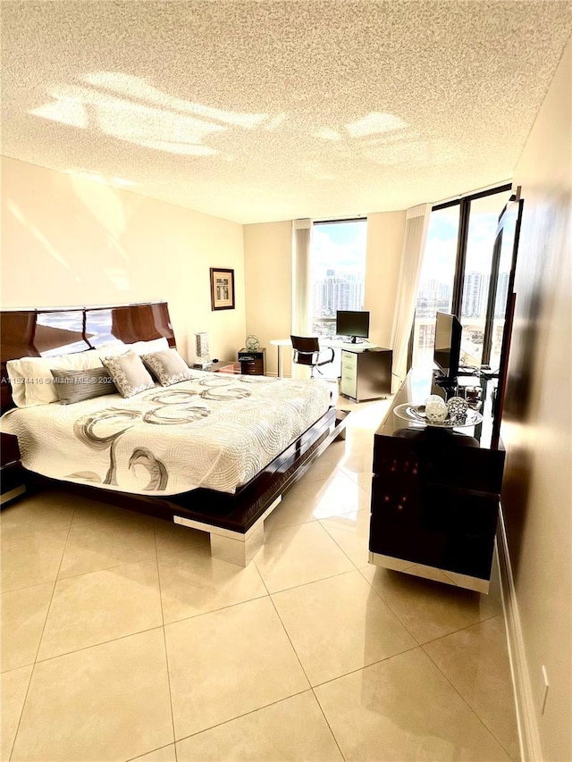 bedroom featuring light tile patterned floors, a textured ceiling, and a wall of windows