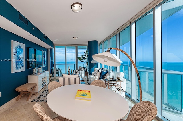 dining room featuring light tile flooring, expansive windows, and a water view