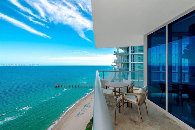 balcony with a water view and a view of the beach