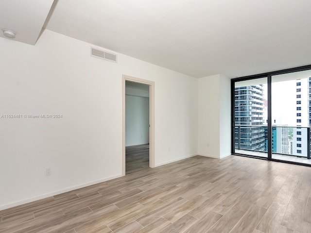 unfurnished room featuring floor to ceiling windows and light hardwood / wood-style floors