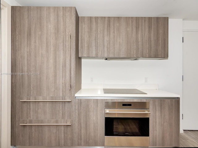 kitchen featuring light brown cabinets, cooktop, and oven