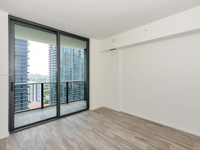 spare room with expansive windows and light wood-type flooring