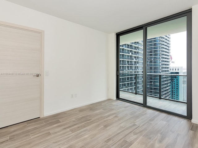 spare room with expansive windows and light hardwood / wood-style flooring