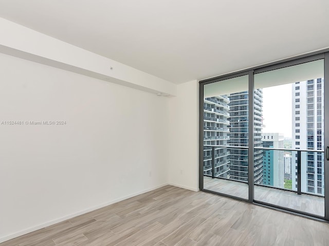 unfurnished room featuring floor to ceiling windows and light wood-type flooring