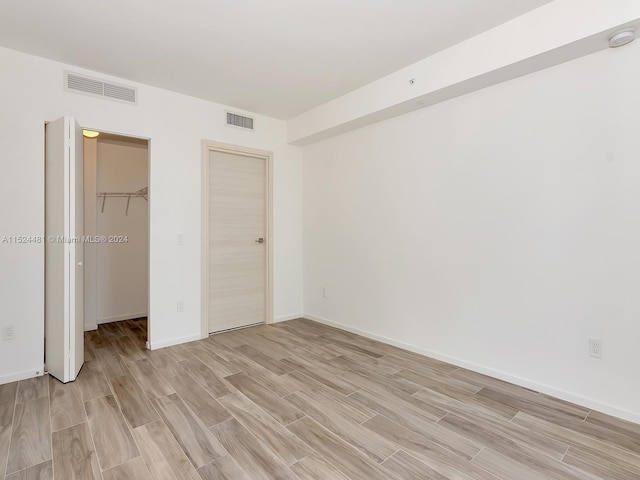 unfurnished bedroom featuring a walk in closet, a closet, and light wood-type flooring