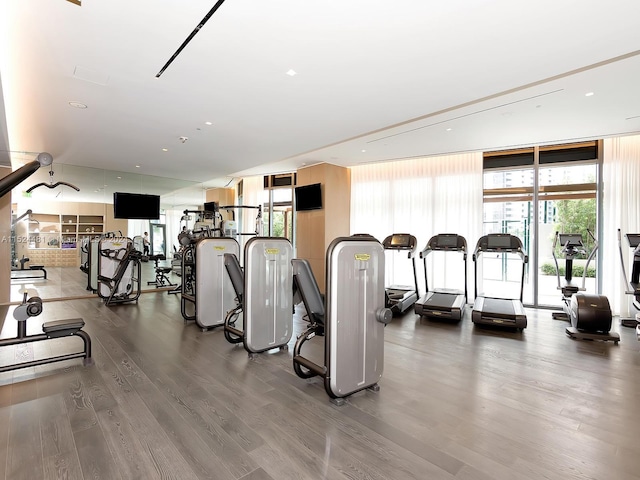 workout area with floor to ceiling windows and dark hardwood / wood-style flooring