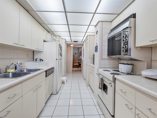 kitchen featuring tile walls, white appliances, sink, light tile floors, and white cabinets