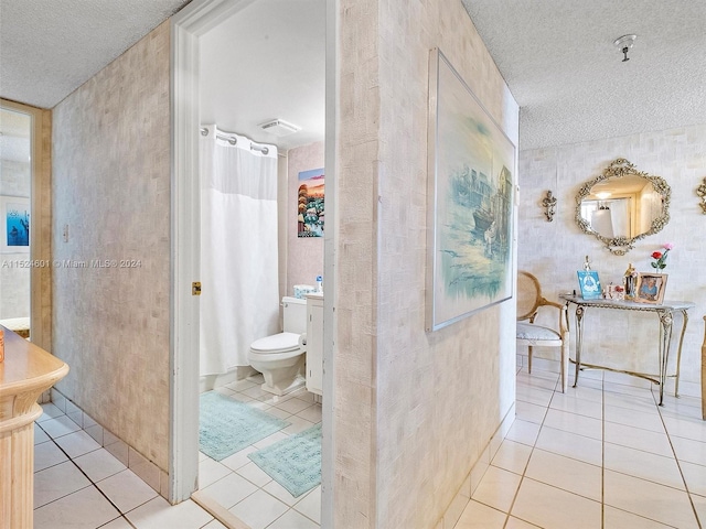 corridor with light tile flooring and a textured ceiling