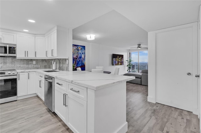 kitchen featuring kitchen peninsula, white cabinets, light wood-type flooring, and appliances with stainless steel finishes