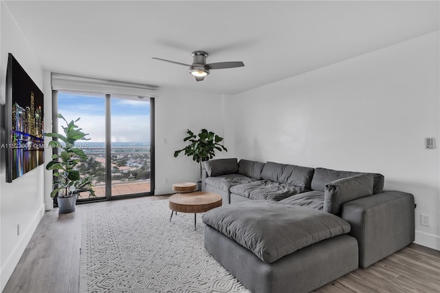 living area with wood finished floors, baseboards, and ceiling fan