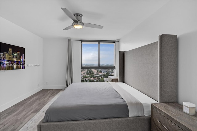 bedroom featuring expansive windows, a ceiling fan, baseboards, and wood finished floors