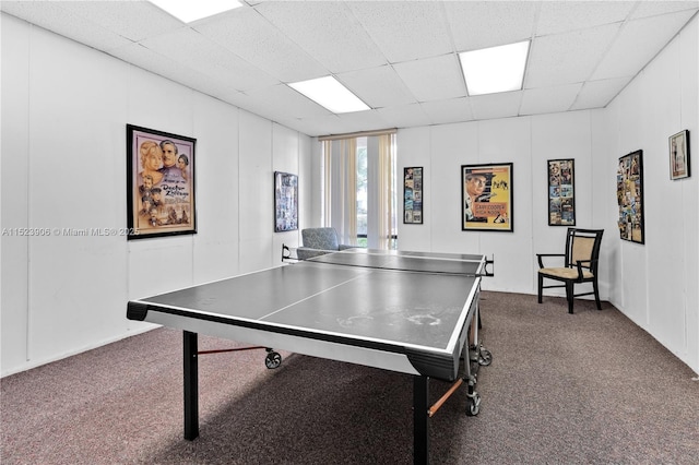 playroom with a decorative wall, a drop ceiling, and dark carpet