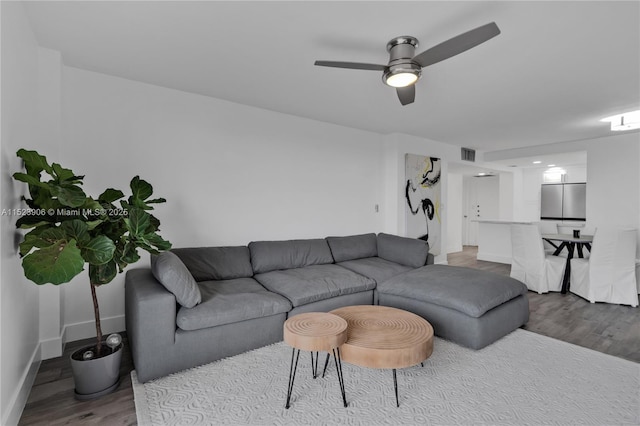 living area with visible vents, ceiling fan, baseboards, and wood finished floors