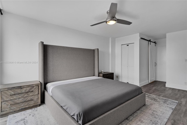 bedroom with a closet, a barn door, hardwood / wood-style flooring, and ceiling fan