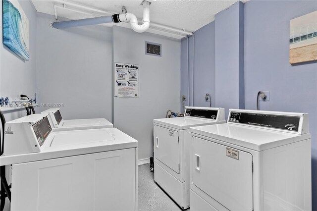 clothes washing area with washer and clothes dryer and a textured ceiling