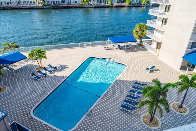 community pool with a water view, fence, and a patio area