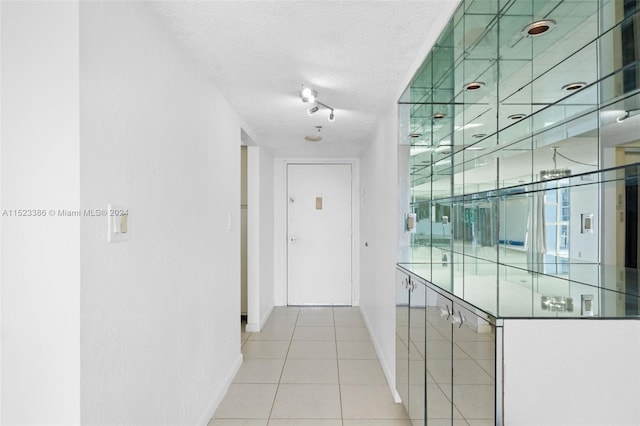 hallway with light tile patterned floors and a textured ceiling