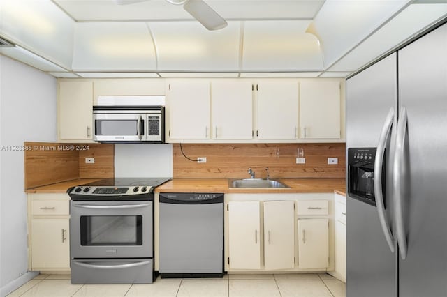 kitchen featuring appliances with stainless steel finishes, light tile patterned floors, sink, and ceiling fan