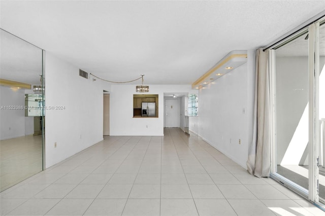 unfurnished living room with a notable chandelier and light tile patterned flooring