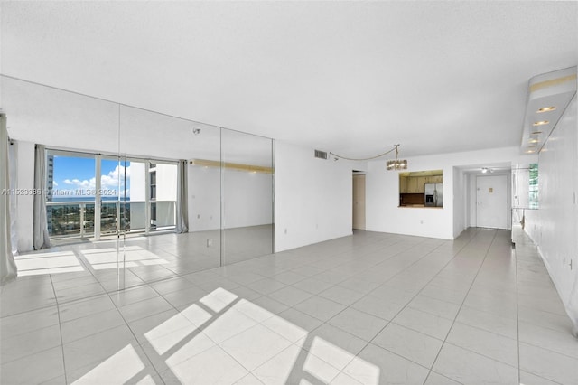 unfurnished living room with light tile patterned flooring, a wall of windows, and plenty of natural light