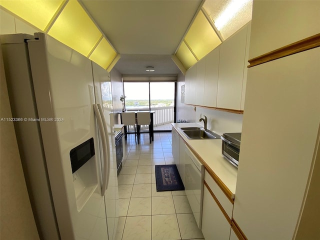 kitchen with light tile flooring, white appliances, white cabinetry, and sink