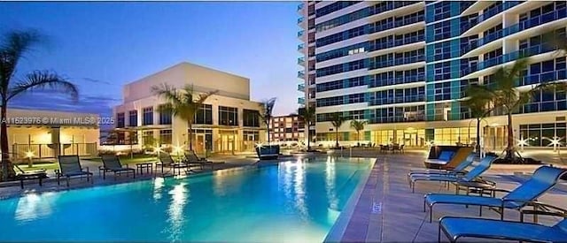 pool at dusk featuring a patio