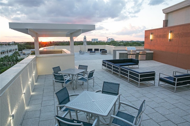 patio terrace at dusk featuring area for grilling and exterior kitchen