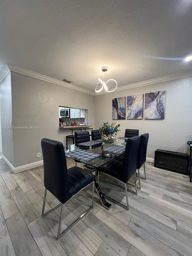 dining room with crown molding, light hardwood / wood-style flooring, a textured ceiling, and an inviting chandelier