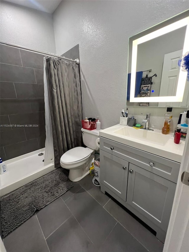 bathroom with vanity, tile floors, toilet, and walk in shower