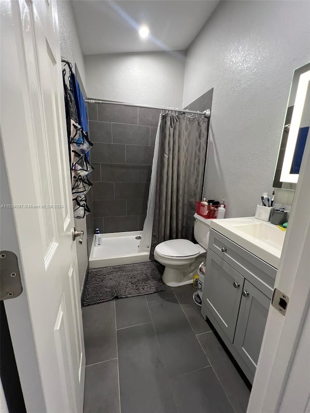 bathroom with walk in shower, toilet, vanity, and tile flooring