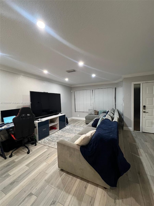 living room with a textured ceiling, crown molding, and light wood-type flooring