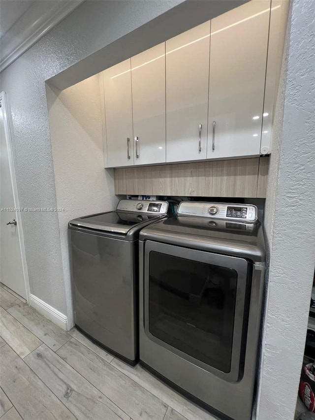 laundry room with cabinets, independent washer and dryer, and light wood-type flooring