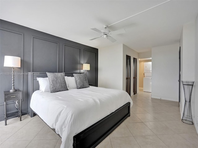 bedroom featuring light tile patterned floors, a decorative wall, and a ceiling fan